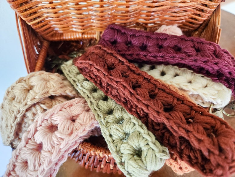 Pode incluir: Uma cesta de vime cheia de tiras de croch&ecirc; em v&aacute;rias cores, incluindo rosa, verde, marrom e bord&ocirc;. As tiras s&atilde;o feitas com um padr&atilde;o de ponto texturizado.