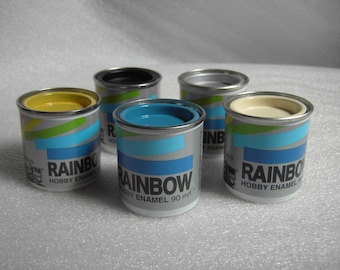 May include: Six small paint cans with colorful lids. The cans are labeled "Rainbow Hobby Enamel 90 ml".