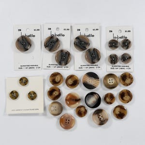 May include: A collection of brown and tan buttons in various sizes. Some buttons are attached to white cards with the text "la-petite" and "GUARANTEED WASHABLE". Button sizes include 1 1/8" (28mm) and 3/4" (19mm).
