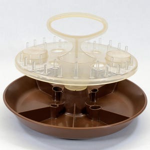 May include: A brown plastic serving tray with a clear plastic top featuring a handle and small pegs. The tray has a circular base and a divided interior. The clear top has two circular areas and a handle.