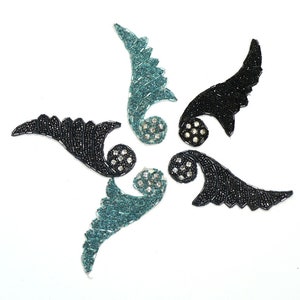 May include: Four decorative embellishments in the shape of stylized wings. Two are black with silver rhinestones and two are teal with silver rhinestones.