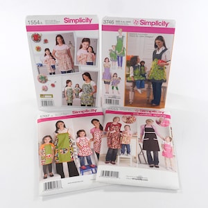 May include: Four Simplicity sewing pattern packets featuring aprons. The packets display images of aprons in various styles and colors, with models wearing the finished products. The packets are labeled with numbers and the Simplicity logo.