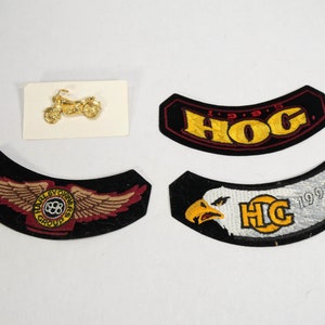 May include: Four Harley Davidson motorcycle patches. Two are black with red trim and yellow lettering. One has a Harley Davidson logo with wings and the other says "HOG 1995". The other two patches are black with white trim and yellow lettering. One has an eagle and says "H.O.G. 1997" and the other has a Harley Davidson logo with wings. A small gold motorcycle pin is also included.