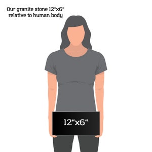 May include: A person holding a black rectangular sign with the text "12"x6" written in white. The sign is being held in front of the person's torso, which is wearing a gray t-shirt.