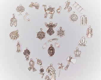 May include: A collection of silver-toned metal charms arranged in a heart shape. The charms include various shapes such as an angel, snowflakes, a camel, a tree, a lighthouse, a crown, an axe, a rose, a shell, a star, and religious symbols.
