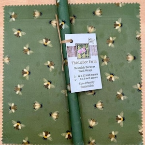 May include: Reusable beeswax food wraps from ThistleBee Farm. The green wraps feature a bee pattern and come in two sizes: 12 x 12 inches and 9 x 9 inches. The wraps are eco-friendly and sustainable.