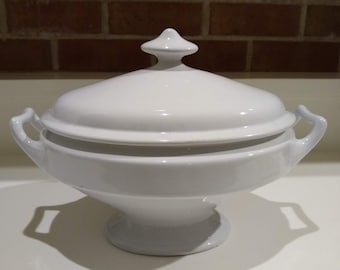May include: White ceramic serving bowl with a lid and two handles. The bowl has a pedestal base.