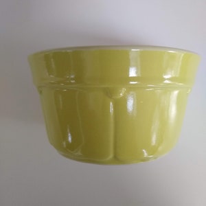 May include: A yellow ceramic mixing bowl with a fluted design. The bowl is glazed and has a glossy finish.