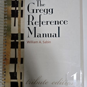 May include: The Gregg Reference Manual, a spiral-bound book with a black and white patterned cover. The title is in black text and the author, William A. Sabin, is in smaller black text. The book is labeled "tribute edition 11".