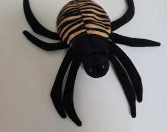 May include: Black and brown striped plush spider toy with red eyes. The spider has eight legs and is made of soft fabric.