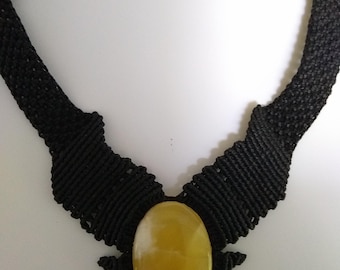 May include: A black macrame necklace with a large yellow oval gemstone pendant.