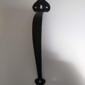 May include: Black metal door handle with a pointed design at the top and bottom. The handle has a keyhole and two small holes on the top.