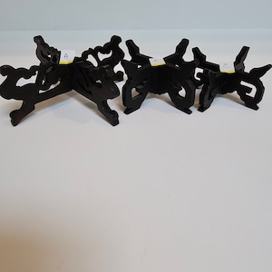 May include: Three black wooden display stands with intricate designs. The stands are labeled A, B, and C.