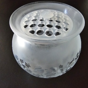 May include: A frosted glass vase with a clear plastic insert with holes for flower stems. The vase has a textured, frosted finish.