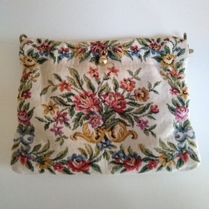 May include: A vintage floral tapestry clutch bag with a gold clasp and a gold tone metal chain strap.