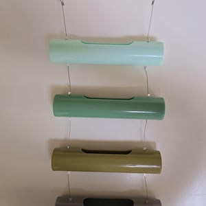 May include: Four hanging planters made of plastic in different colors: light green, dark green, brown, and gray. Each planter has a small opening on the side for plants.