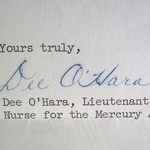 May include: A handwritten note on textured paper, signed "Dee O'Hara." The signature is in blue ink, with the typed text below identifying her as a Lieutenant and Nurse for the Mercury Astronauts.