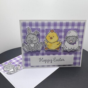 Cartão de feliz Páscoa. Fundo xadrez roxo e branco. Coelho, pintinho e cordeiro. Envelope coordenado com coelho e guingão.