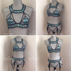May include: A black chainmail bra and belt set with iridescent green triangle-shaped embellishments. The set is displayed on a white mannequin.