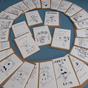 May include: A collection of blank greeting cards featuring black and white illustrations of dogs. The cards are printed on brown cardstock and have a variety of messages, including "Happy Birthday", "Get Well Soon", "Thinking of You", and "Thank You".