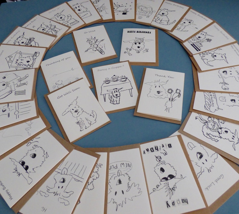 May include: A collection of blank greeting cards featuring black and white illustrations of dogs. The cards are printed on brown cardstock and have a variety of messages, including "Happy Birthday", "Get Well Soon", "Thinking of You", and "Thank You".