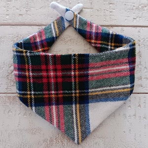 May include: A red, white, and green plaid bandana with a white button closure. The bandana is folded into a triangle shape.