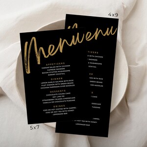 May include: Black menu cards with gold lettering, featuring a handwritten "Menu" title. The cards list appetizers, dinner, desserts, and drinks. One card is 5x7 inches, and the other is 4x9 inches. The background is a white, textured surface.