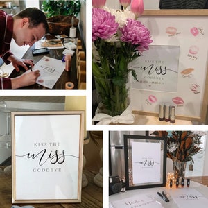 以下が含まれることがあります： 黒い筆記体で「Kiss the Miss Goodbye」と書かれた額縁付きの看板。看板は、ピンクと赤の様々な色合いの口紅のキスで囲まれている。看板は、ピンクと白の花が飾られた花瓶のあるテーブルの上に置かれている。