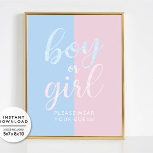 Könnte beinhalten: Ein gerahmtes Gender-Reveal-Schild mit goldenem Rahmen. Das Schild ist vertikal in blaue und rosa Abschnitte unterteilt. Die Worte "boy or girl" sind in glitzernder Schrift geschrieben. Darunter steht "PLEASE WEAR YOUR GUESS!". Erhältlich in 12,7 x 17,8 cm und 20,3 x 25,4 cm.