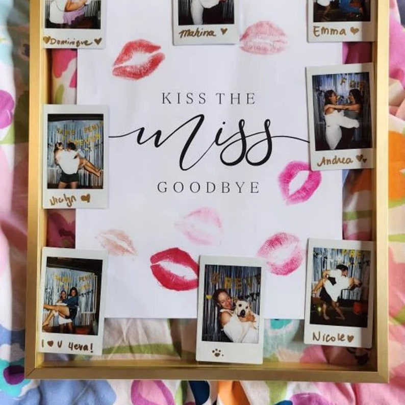 以下が含まれることがあります： 白い背景に「Kiss the Miss Goodbye」という文字が書かれた金色の額縁。額縁の中には、それぞれ名前が書かれたポラロイド写真がいくつか飾られています。白い背景には、赤い口紅のキスがいくつかあります。