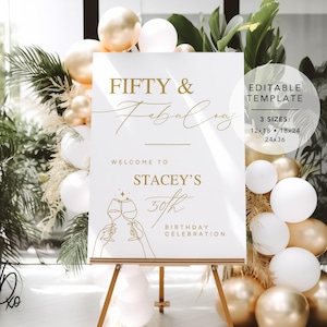 以下が含まれることがあります： 「フィフティ＆ファビュラス」と「ステイシーの50回目の誕生日のお祝い」と金色の文字で書かれた白い看板。看板はイーゼルに置かれ、背景には金色と白の風船がある。