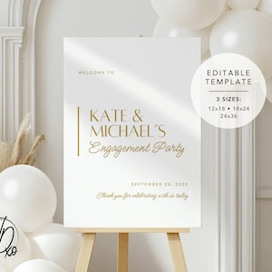 May include: A white welcome sign with gold text that reads "Welcome to Kate & Michael's Engagement Party" with the date "September 25, 2025" and the text "Thank you for celebrating with us today". The sign is on an easel and there are white balloons in the background.