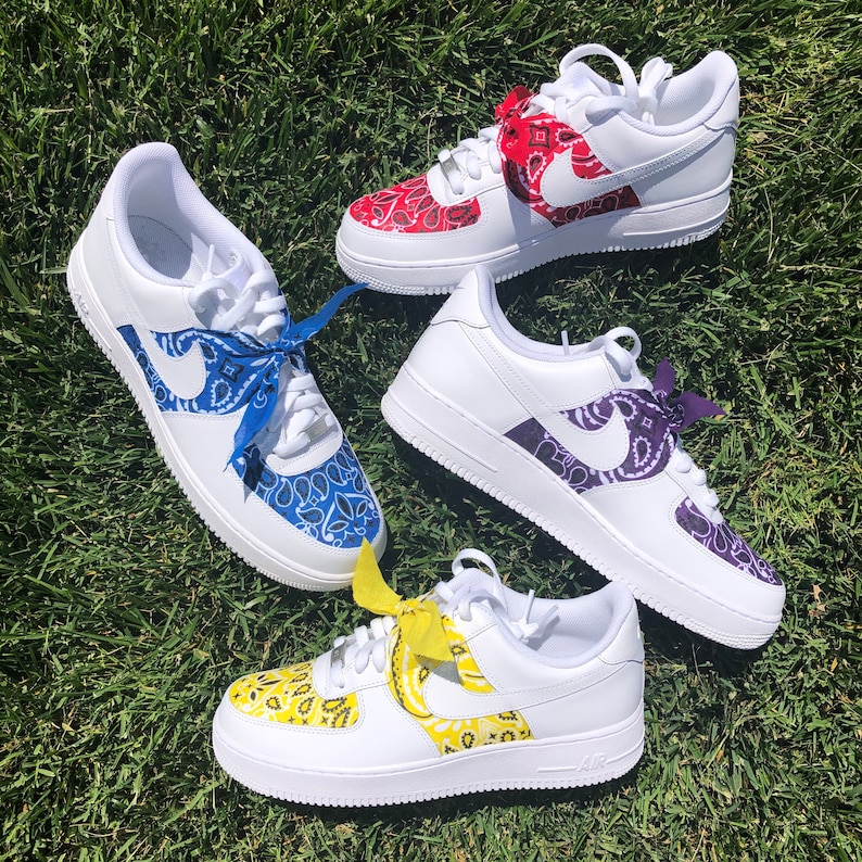 May include: Four white sneakers with custom bandana designs in red, blue, purple, and yellow. Each shoe features a different color bandana pattern on the Nike swoosh and toe area, with matching bandana laces.