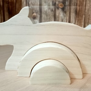 Pode incluir: Um brinquedo de madeira em forma de hipopótamo, com um acabamento em madeira clara e natural. O hipopótamo é feito de várias peças interligadas, incluindo duas peças arqueadas e o corpo do hipopótamo. Destinado a crianças.