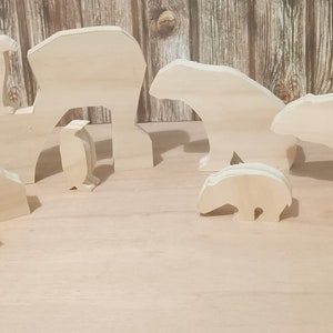 May include: A set of wooden animal cutouts, including a bear, a penguin, and a polar bear. The cutouts are unpainted and ready to be decorated.