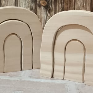 Könnte beinhalten: Zwei unfertige Holzbögen in Regenbogenform, jeder mit drei Schichten, übereinander gestapelt. Die Bögen sind aus Naturholz gefertigt und haben eine glatte, geschliffene Oberfläche.
