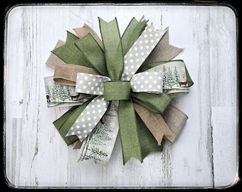 May include: A green, brown, and white patterned bow with a rustic farmhouse style. The bow is made of burlap, polka dot fabric, and a green ribbon.
