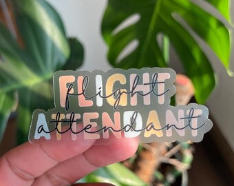 May include: A clear sticker with the words "flight attendant" in a colorful, layered font. The sticker has a translucent background and is printed on a white surface.