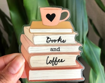 Puede incluir: Una pila de libros con una taza de café rosa en la parte superior. Los libros son de color marrón, blanco y crema. El texto "Books and coffee" está escrito en los libros.