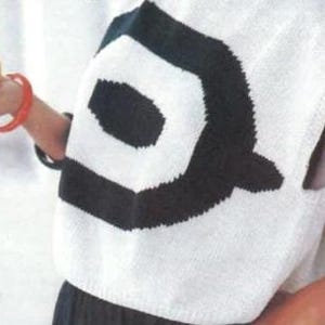 Puede incluir: Un su&eacute;ter blanco sin mangas con un gran dise&ntilde;o geom&eacute;trico negro en la espalda. El su&eacute;ter est&aacute; hecho de un material de punto. Una persona sostiene una fruta naranja y lleva una pulsera roja.