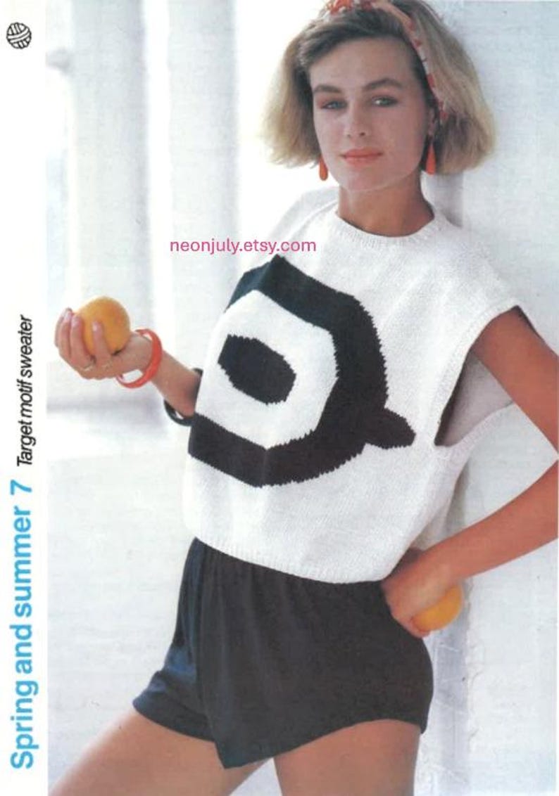 Puede incluir: Top sin mangas de punto blanco con un gran dise&ntilde;o geom&eacute;trico negro. El texto "Spring and summer 7 Target motif sweater" es visible. La persona lleva pantalones cortos negros y sostiene una naranja.