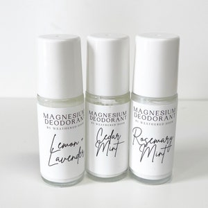 Pode incluir: Tr&ecirc;s frascos de desodorizante roll-on brancos com r&oacute;tulos pretos. Os r&oacute;tulos dizem "Magnesium Deodorant by Weathered Door" e listam os aromas: "Lemon + Lavender", "Cedar Mint" e "Rosemary Mint".