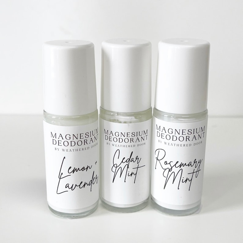 Pode incluir: Tr&ecirc;s frascos de desodorizante roll-on brancos com r&oacute;tulos pretos. Os r&oacute;tulos dizem "Magnesium Deodorant by Weathered Door" e listam os aromas: "Lemon + Lavender", "Cedar Mint" e "Rosemary Mint".