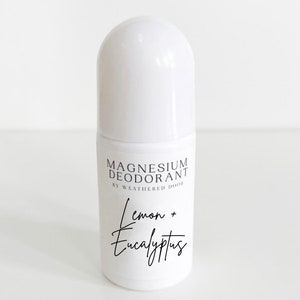 Pode incluir: Frasco de desodorizante roll-on branco com um r&oacute;tulo preto que diz "Magnesium Deodorant by Weathered Door" e "Lemon + Eucalyptus".