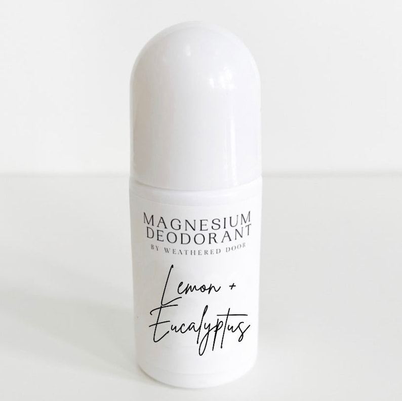 Pode incluir: Frasco de desodorizante roll-on branco com um r&oacute;tulo preto que diz "Magnesium Deodorant by Weathered Door" e "Lemon + Eucalyptus".