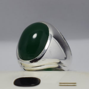 Pode incluir: Um anel de prata com uma grande gema oval de cor verde escura.
