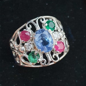 May include: A silver ring with a blue sapphire, red rubies, green emeralds, and a white diamond set in a filigree design.