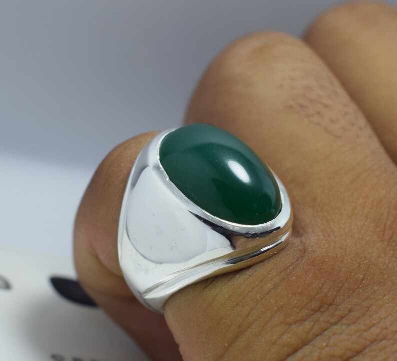 Pode incluir: Um anel de prata com uma grande gema verde oval.
