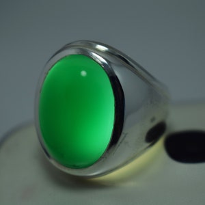 Pode incluir: Um anel de prata com uma gema oval verde brilhante.