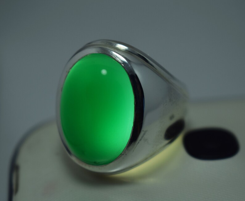 Pode incluir: Um anel de prata com uma gema oval verde brilhante.